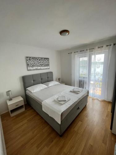 a white bedroom with a large bed and a window at Guest House Matana in Sobra