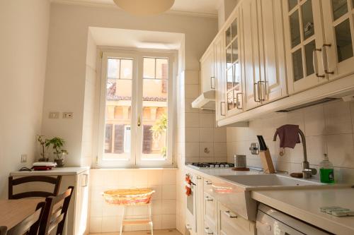 a kitchen with white cabinets and a sink and a window at Borghese Magnolia Suite in Rome
