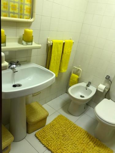 a bathroom with a sink and a toilet and yellow towels at T1 - Praia da Rocha - com Vistas de Mar e Terraço in Portimão