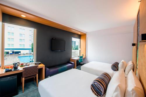 a hotel room with two beds and a desk at Aloft Bengaluru Whitefield in Bangalore