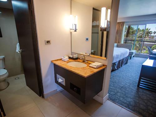 a bathroom with a sink and a bed and a mirror at Hotel Lucerna Mexicali in Mexicali