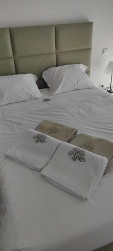 a white bed with two white towels on it at VillaCella - Gerês in Vieira do Minho