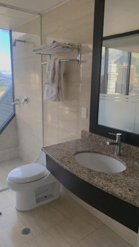a bathroom with a sink and a toilet and a mirror at HOTEL CHACAO SUITES in Caracas