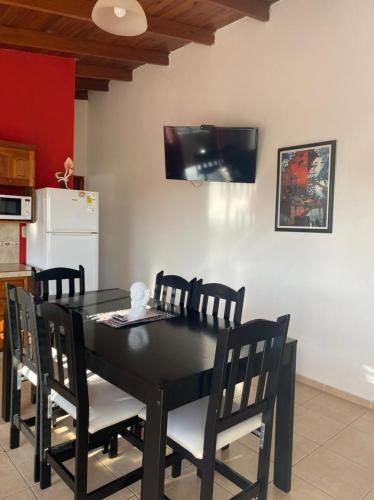mesa de comedor negra con sillas y TV en la pared en Departamentos Lo De Juan en Federación