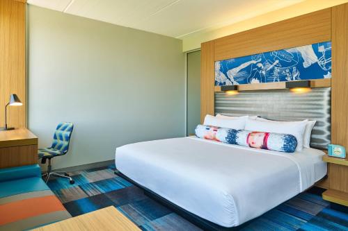 a bedroom with a large white bed and a chair at Aloft Hotel Frisco in Frisco