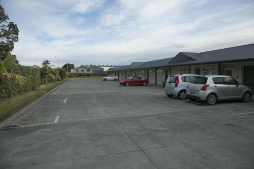 two cars parked in a parking lot next to a building at Captain Cook Motor Lodge in Gisborne
