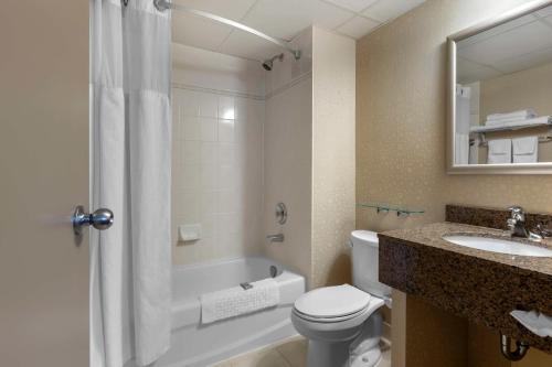 a bathroom with a toilet and a sink and a tub at Best Western Halton Hills in Georgetown