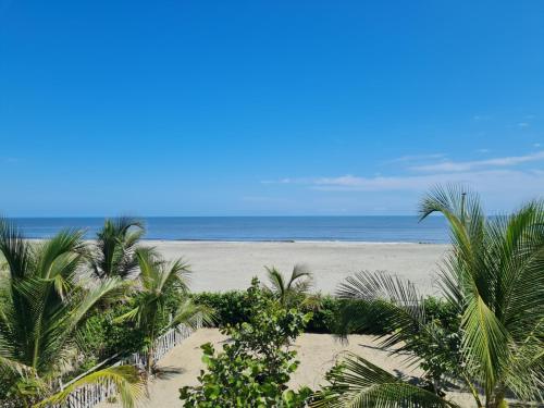 a view of a beach with palm trees and the ocean at CHEVERE BEACH CABAÑAS SAS in Puebloviejo