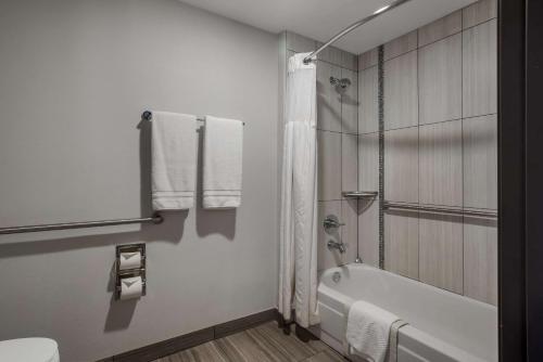 a white bathroom with a tub and a toilet at Hotel 28 Boise Airport, Ascend Hotel Collection in Boise