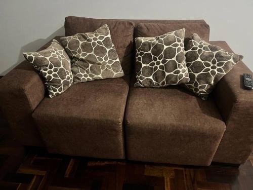 a brown couch with three pillows on it at Ap Central c/ Garagem in Ponta Grossa