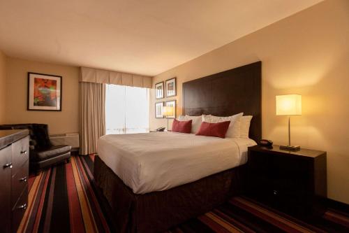 um quarto de hotel com uma cama grande e uma cadeira em Clarion Hotel New Orleans - Airport & Conference Center em Kenner