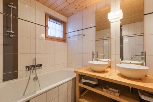 een badkamer met 2 wastafels en een bad bij Montebello Cozy, classic Swiss chalet with stunning views in La Tzoumaz
