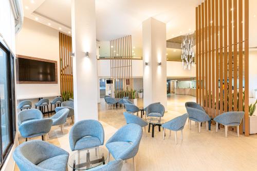 a waiting room with blue chairs and tables at Hotel Casino Internacional in Cúcuta