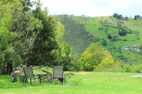 two chairs sitting in a field with a view of a hill at Casa Caliza Bienestar & Descanso in El Carmen