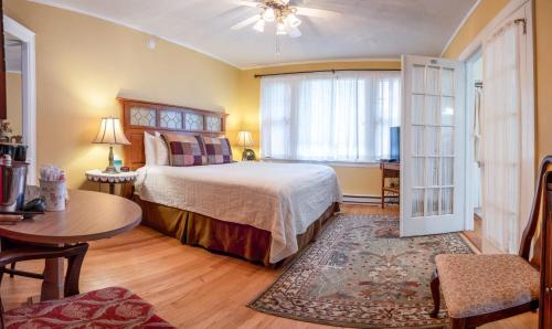 a bedroom with a bed and a table and a window at Heathwood Inn in Bar Harbor