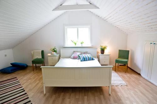 a bedroom with a bed and two green chairs at Nommen Fishing Cottages in Vetlanda