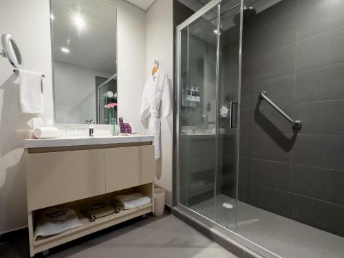 een badkamer met een douche, een wastafel en een glazen douchecabine bij HS HOTSSON Long Stay CDMX Condesa Sur in Mexico-Stad