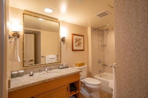a bathroom with a sink and a toilet and a mirror at Embassy Suites by Hilton Waikiki Beach Walk in Honolulu