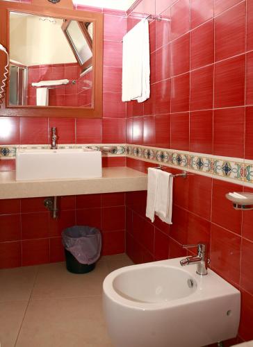 a red tiled bathroom with a sink and a toilet at Villa Cristina in Giardini Naxos