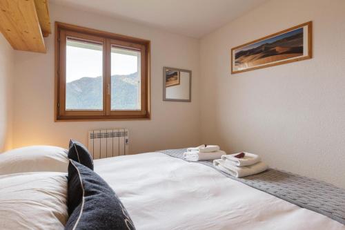 a bedroom with a bed with white sheets and a window at La Taniere - Cozy chalet with incredible views and parking in La Tzoumaz
