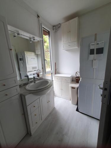 a white kitchen with a sink and a refrigerator at Villa "Le Mirage" in Cap-Ferret