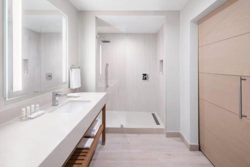 a white bathroom with a sink and a shower at Courtyard by Marriott Port of Spain in Port-of-Spain