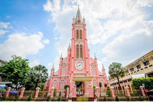 um grande edifício cor-de-rosa com uma torre de relógio em Cubicity Hidden House em Ho Chi Minh