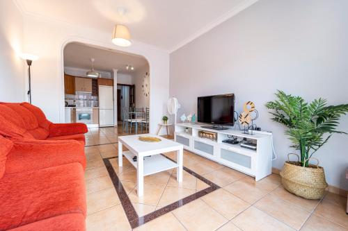 a living room with a red couch and a tv at El Secreto del Norte in Las Palmas de Gran Canaria