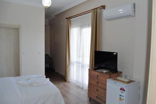 Dormitorio con cama y tocador con TV en BEYAZ KONAK Güre Butik Otel, en Edremit