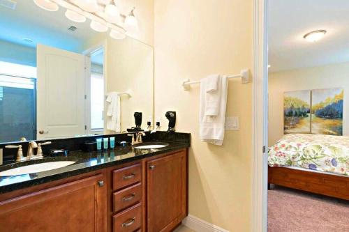 a bathroom with a sink and a mirror and a bed at Deluxe Stay w Pool Spa Game Room BBQ Grill in Orlando