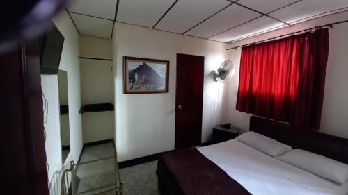 a bedroom with a bed and a red window at HOTEL DEL PARQUE in Calarcá