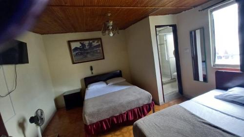 a small bedroom with two beds and a window at HOTEL DEL PARQUE in Calarcá