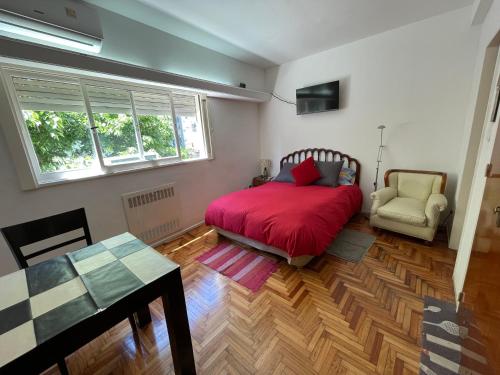 1 dormitorio con 1 cama roja y 1 silla en Imperdible Monoambiente en Palermo Chico 10min Aeroparque 100m Mater Dei en Buenos Aires