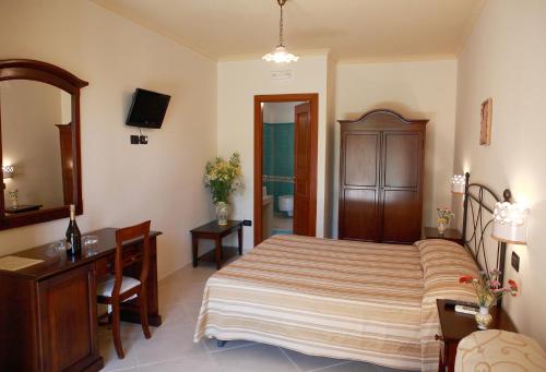 a bedroom with a bed and a desk and a mirror at Villa Cristina in Giardini Naxos