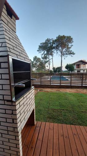 una barbacoa en una terraza de madera junto a un campo en Chalés Ilha da Mata Pousada, en Florianópolis