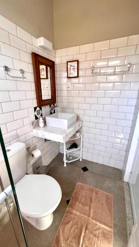 a white bathroom with a toilet and a sink at Flats Naturando's in Buritama