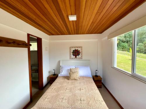 1 dormitorio con 1 cama con techo de madera en Sitio Haras Vitoria, en Teresópolis