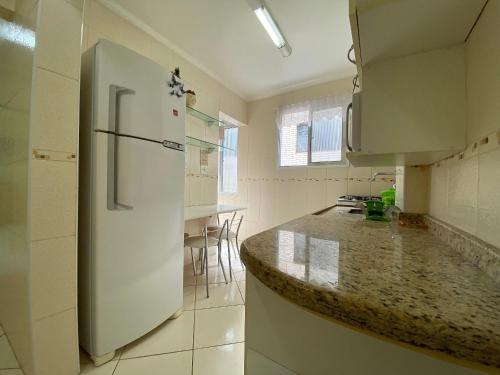 a kitchen with a white refrigerator and a counter at Pé na areia canto do forte II in Praia Grande