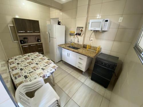 a small kitchen with a refrigerator and a sink at Pé na areia canto do forte II in Praia Grande