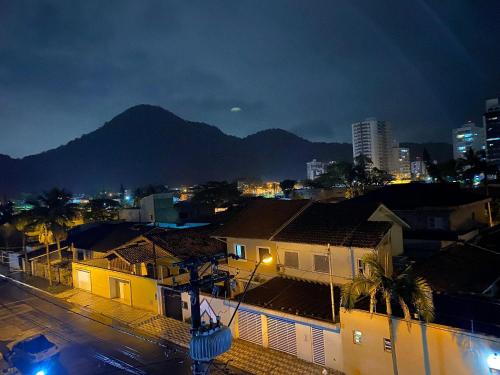 a city at night with buildings and a mountain at Pé na areia canto do forte II in Praia Grande