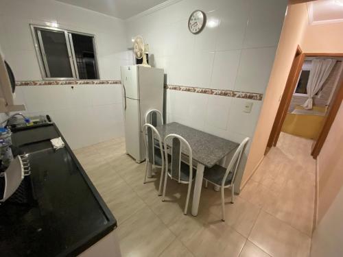 a small kitchen with a table and a refrigerator at Pé na areia canto do forte II in Praia Grande