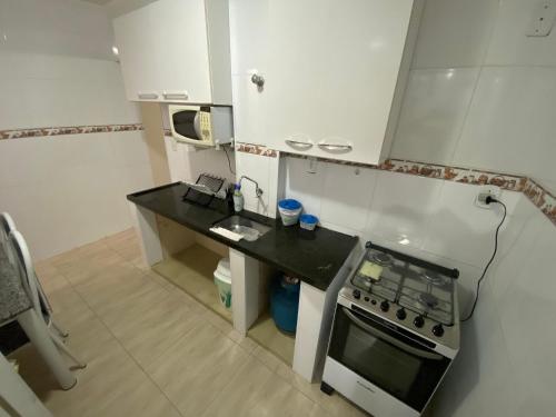 a small kitchen with a stove and a microwave at Pé na areia canto do forte II in Praia Grande