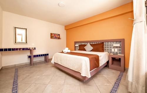 - une chambre avec un grand lit aux murs orange dans l'établissement El Jazmin de Zanya, à Dolores Hidalgo