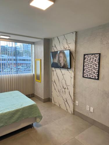 Un dormitorio con una cama y un televisor en una pared. en Lindo Apt de 1 quarto no Sudoeste 103, próximo do centro de convenções Ulysses Guimarães, mane garrincha e ministérios, en Brasilia