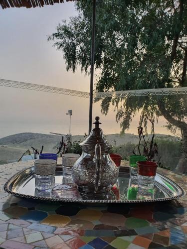 una mesa con un jarrón y gafas. en maison alhaj en Tánger