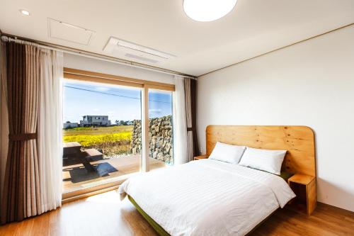 1 dormitorio con cama y ventana grande en Joyuam Jeju, en Seogwipo