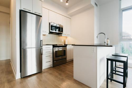 a kitchen with a stainless steel refrigerator and white cabinets at Cozy & Contemporary Suite - Easy Access to Everything in Richmond Hill