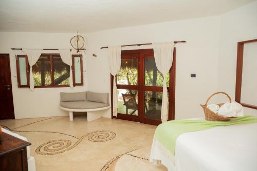 a bedroom with a bed and a chair and a window at Casa Takywara in Holbox Island