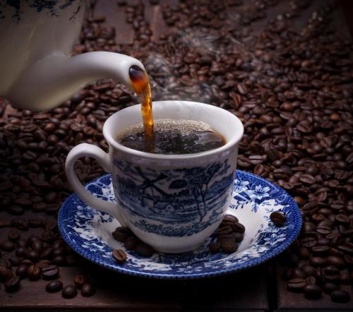 a cup of coffee on a saucer with coffee beans at 31st December Farms And Estates Munnar in Munnar