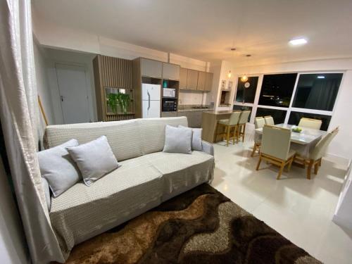 a living room with a couch and a dining room at Glamour Meia Praia in Itapema